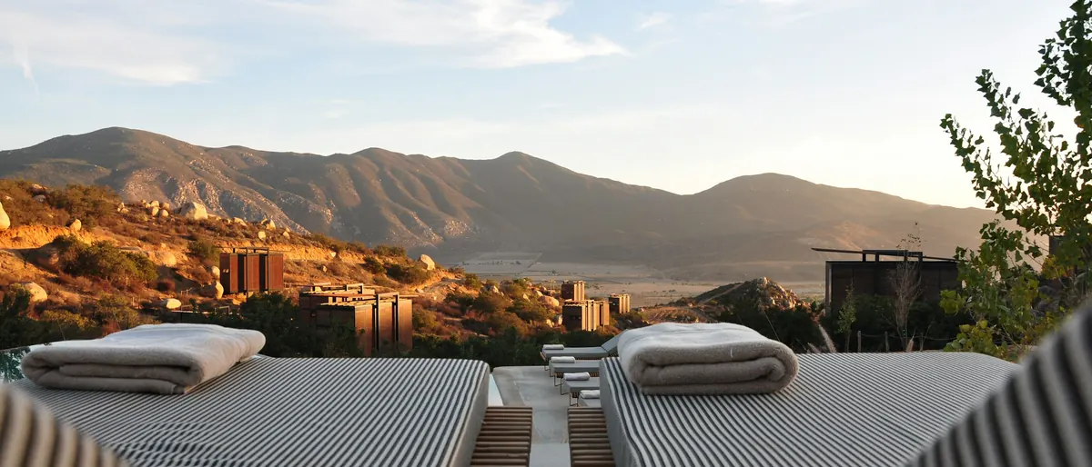 Two sun loungers on a terrace looking out to dry mountains under a pale sky
