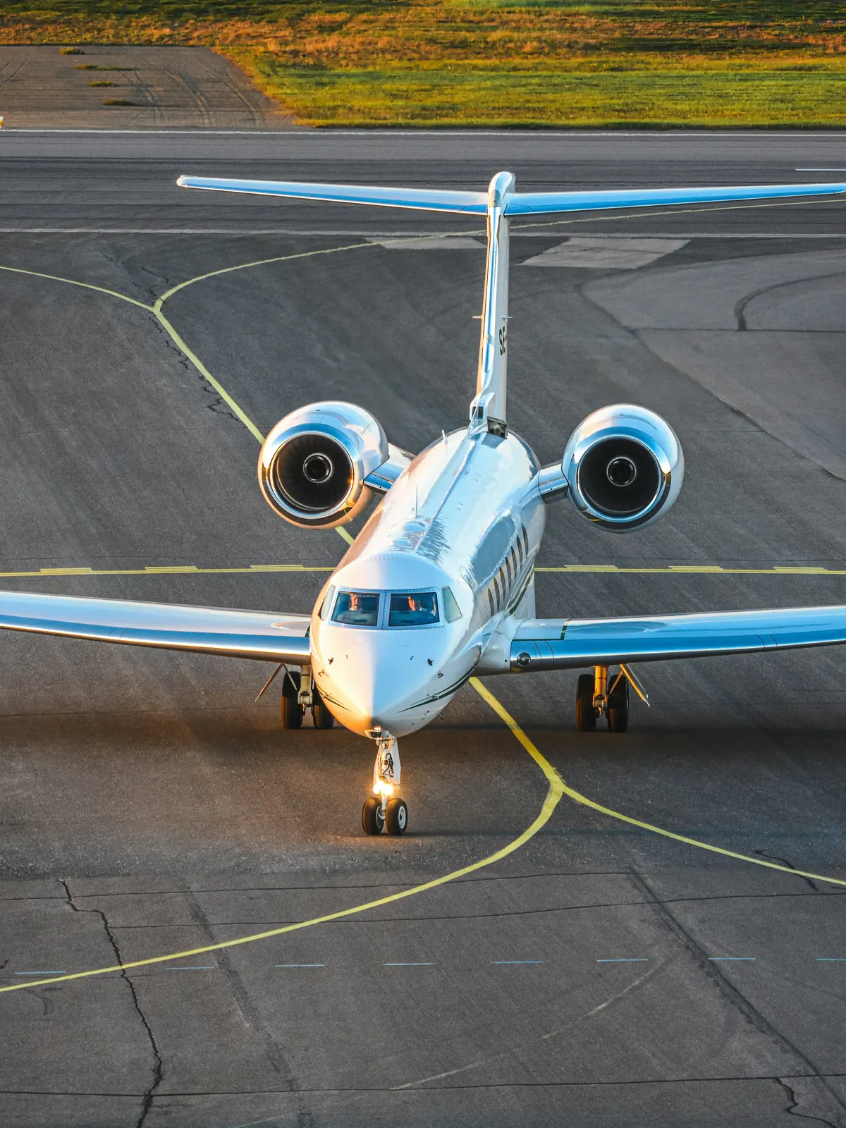 Business jet taxiing toward the camera on a sunny apron