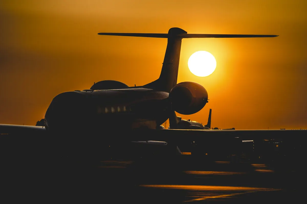 Business jet silhouetted against a low orange sun